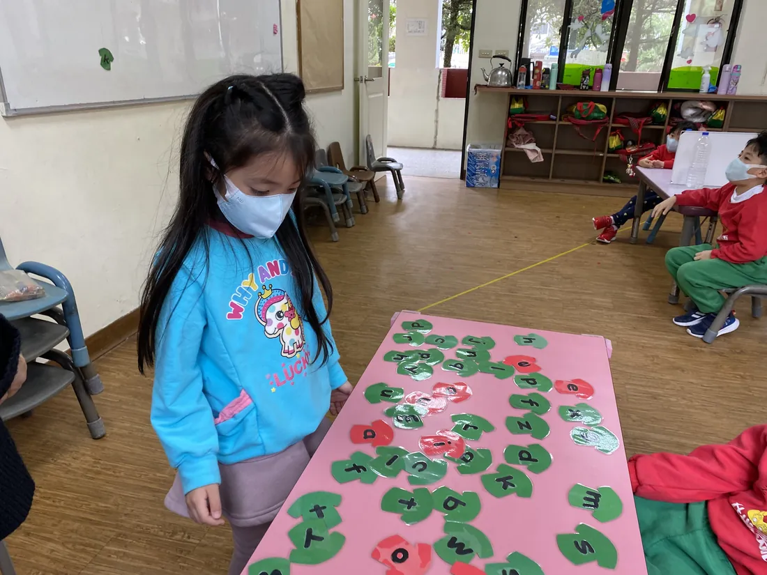 孩子專注地拼組英文字母教具，露出笑容
